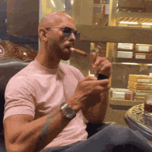 a bald man wearing sunglasses and a watch is smoking a cigar
