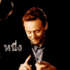 a man in a suit is making a funny face and pointing at something .