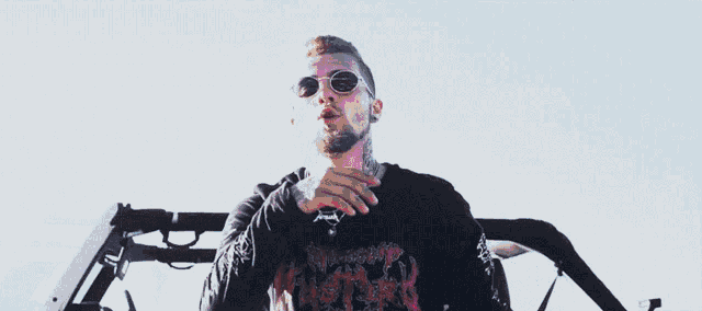 a man wearing sunglasses and a black shirt with the word nirvana on it