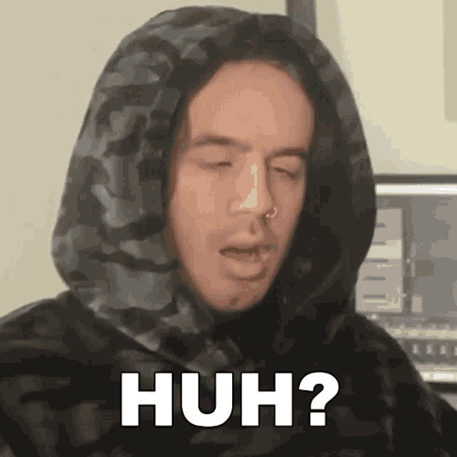 a man wearing a hooded sweatshirt is making a funny face and says huh ?