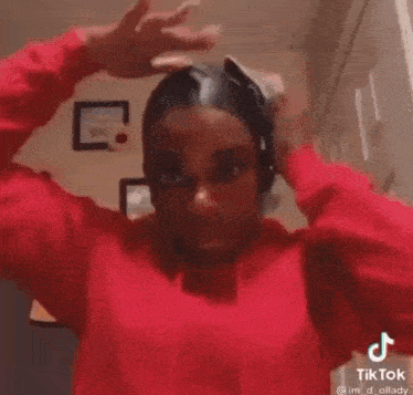 a woman in a red sweatshirt is washing her hair in a bathroom .