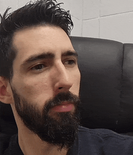 a man with a beard sits in a chair with his eyes closed
