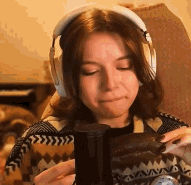 a woman wearing headphones is sitting in a chair holding a coffee mug .