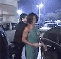 a man and a woman are standing next to each other in a parking lot .