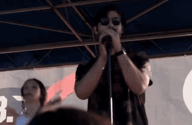 a man singing into a microphone in front of a sign that says 3