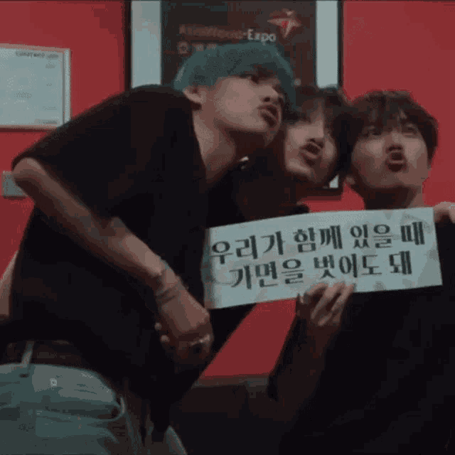 a group of young men are posing for a picture and one of them is holding a sign that says ' korean ' on it