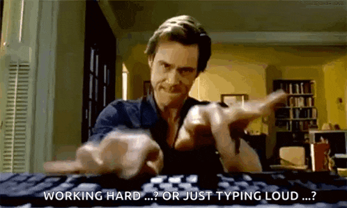 a man is typing on a computer keyboard and pointing at the camera .