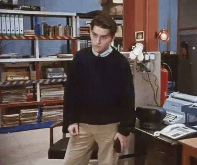 a man in a black sweater is standing in front of a telephone