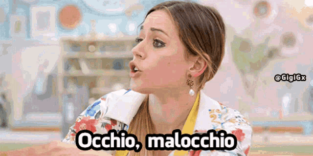 a woman in a floral shirt is saying occhio malocchio