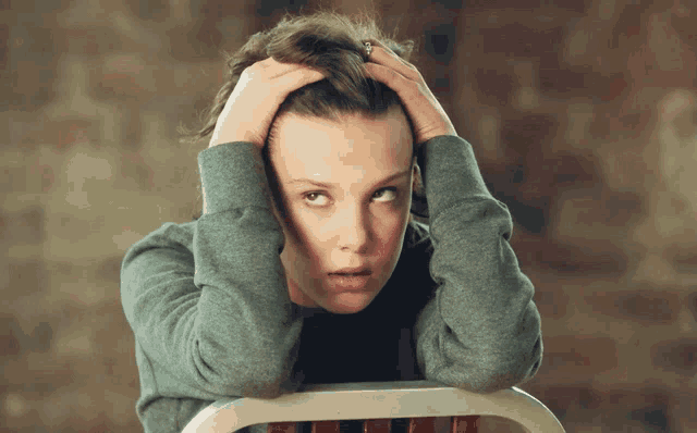 a woman sitting in a chair holding her head with her hands