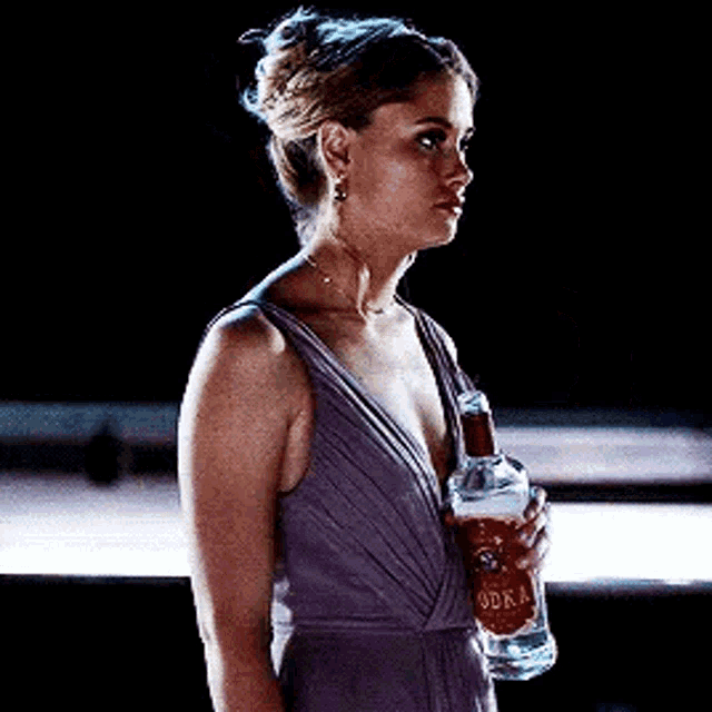 a woman in a dress is holding a bottle of vodka