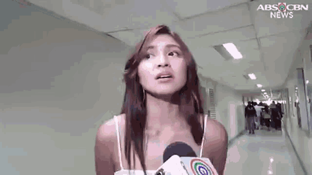 a woman is holding a microphone in a hallway and talking into it .