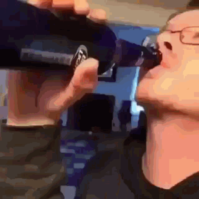a man with glasses is drinking from a bottle that says coca cola on it
