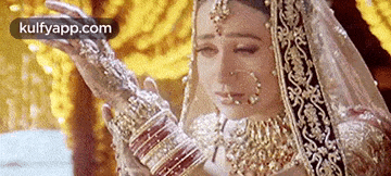a bride in a wedding dress is holding a bunch of bangles .