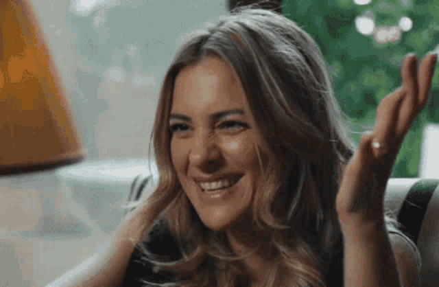 a woman is sitting on a couch making a funny face and smiling .