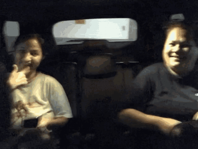 two people sitting in the back seat of a car