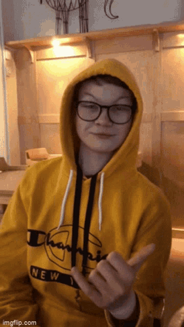 a young man wearing a yellow champion hoodie and glasses