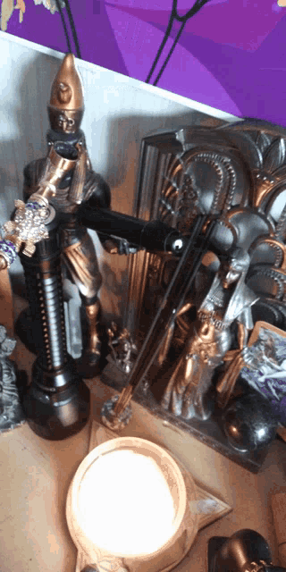 a statue of a man holding a cane sits on a table next to a candle