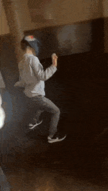 a person is dancing in a dark room while wearing a hat .