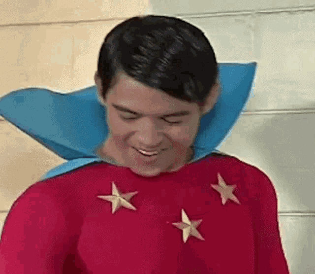 a man is wearing a red superhero costume with blue cape and stars on the chest .