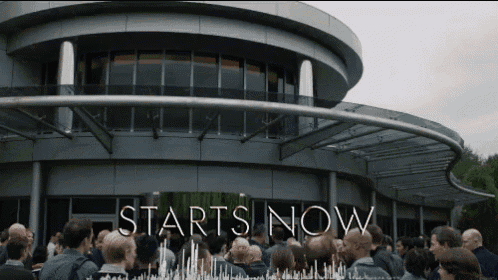 a crowd of people gathered outside of a building that says starts now