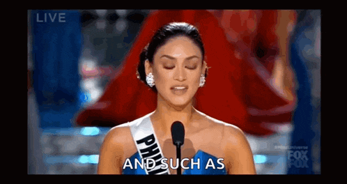 a woman in a blue dress is standing in front of a microphone and saying `` and such as '' .