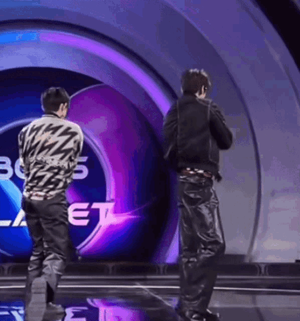 two men are dancing on a stage in front of a sign that says ' boys '