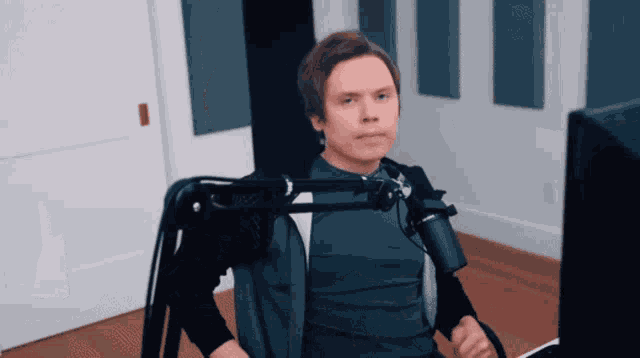 a man is sitting in front of a microphone and a computer