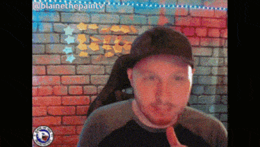 a man giving a thumbs up in front of a brick wall with stickers on it