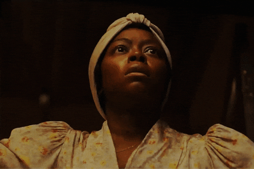 a woman wearing a white turban looks up at the camera