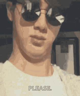 a man wearing sunglasses and a white shirt is making a face .
