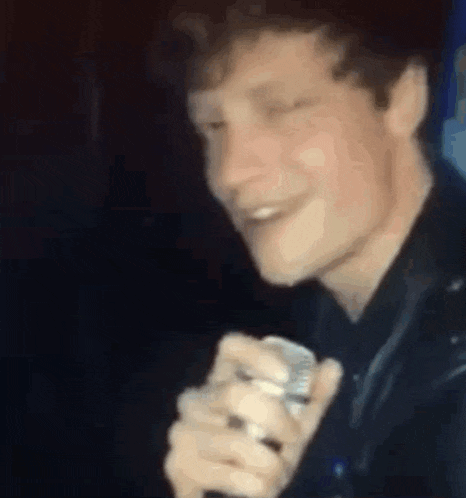 a close up of a man holding a microphone and singing into it .