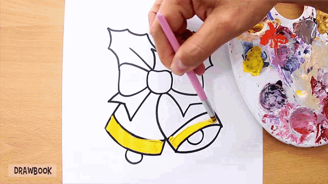 a person is painting a christmas bell with yellow