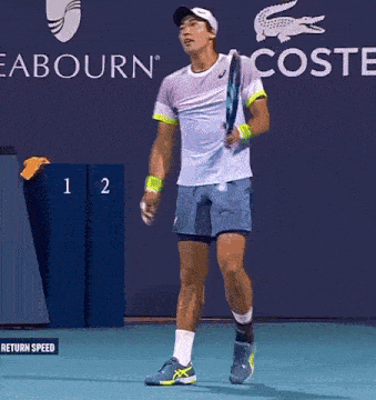 a man is holding a tennis racquet in front of a lacoste sign