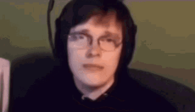 a young man wearing headphones and glasses is sitting in a chair .