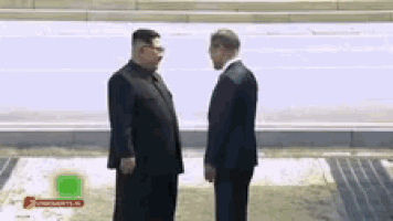 two men in suits are standing next to each other on the sidewalk .