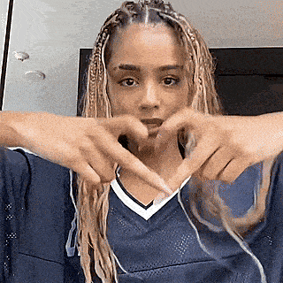 a woman is making a heart with her hands .