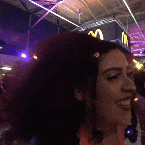 a woman smiles in front of a mcdonalds sign
