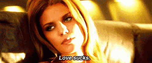 a woman is sitting on a couch and saying `` love sucks . ''
