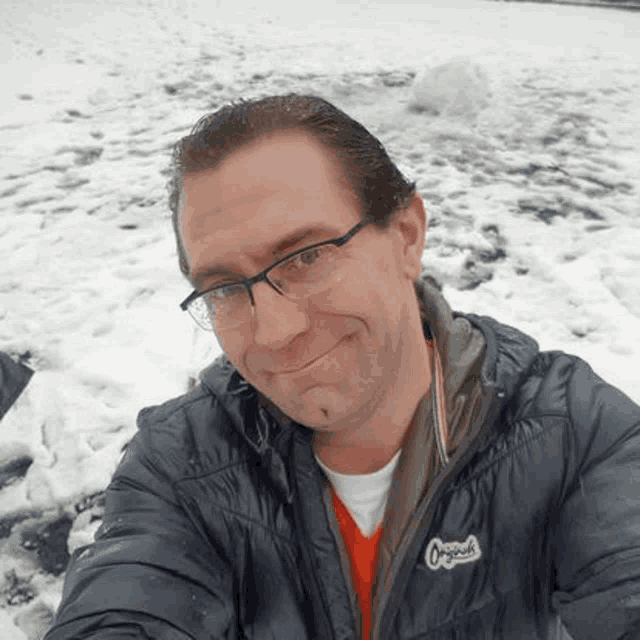 a man with glasses is taking a selfie in the snow .