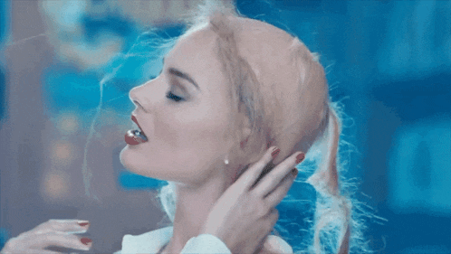 a close up of a woman 's face with blonde hair and red nails