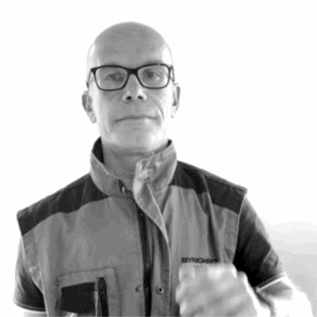 a bald man wearing glasses and a vest that says synchem on it