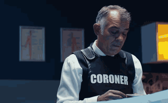 a man wearing a black vest that says coroner