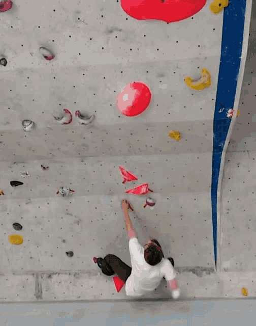 a man climbs a climbing wall with a red ball in the background