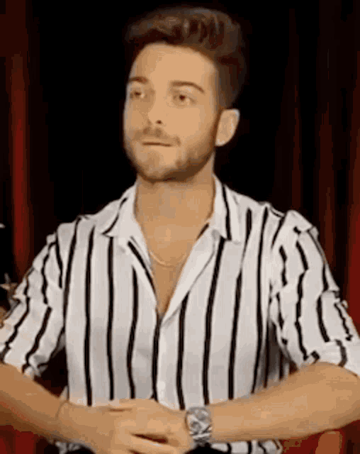 a man with a beard is wearing a black and white striped shirt and a watch .