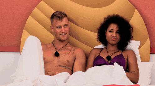 a man and a woman are laying on a bed and the man has a tattoo on his chest that says ' confidence '