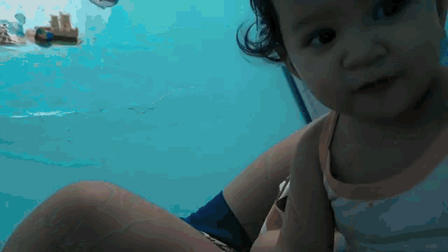 a little girl is sitting in a pool looking at the camera