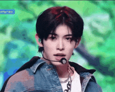a young man wearing a denim jacket and a microphone