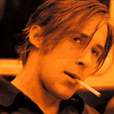 a man with long hair is smoking a cigarette in his mouth .