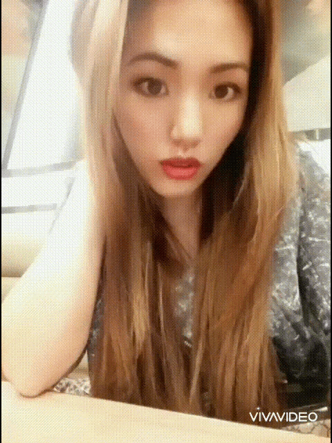 a woman with long blonde hair is sitting at a table with her hand on her head